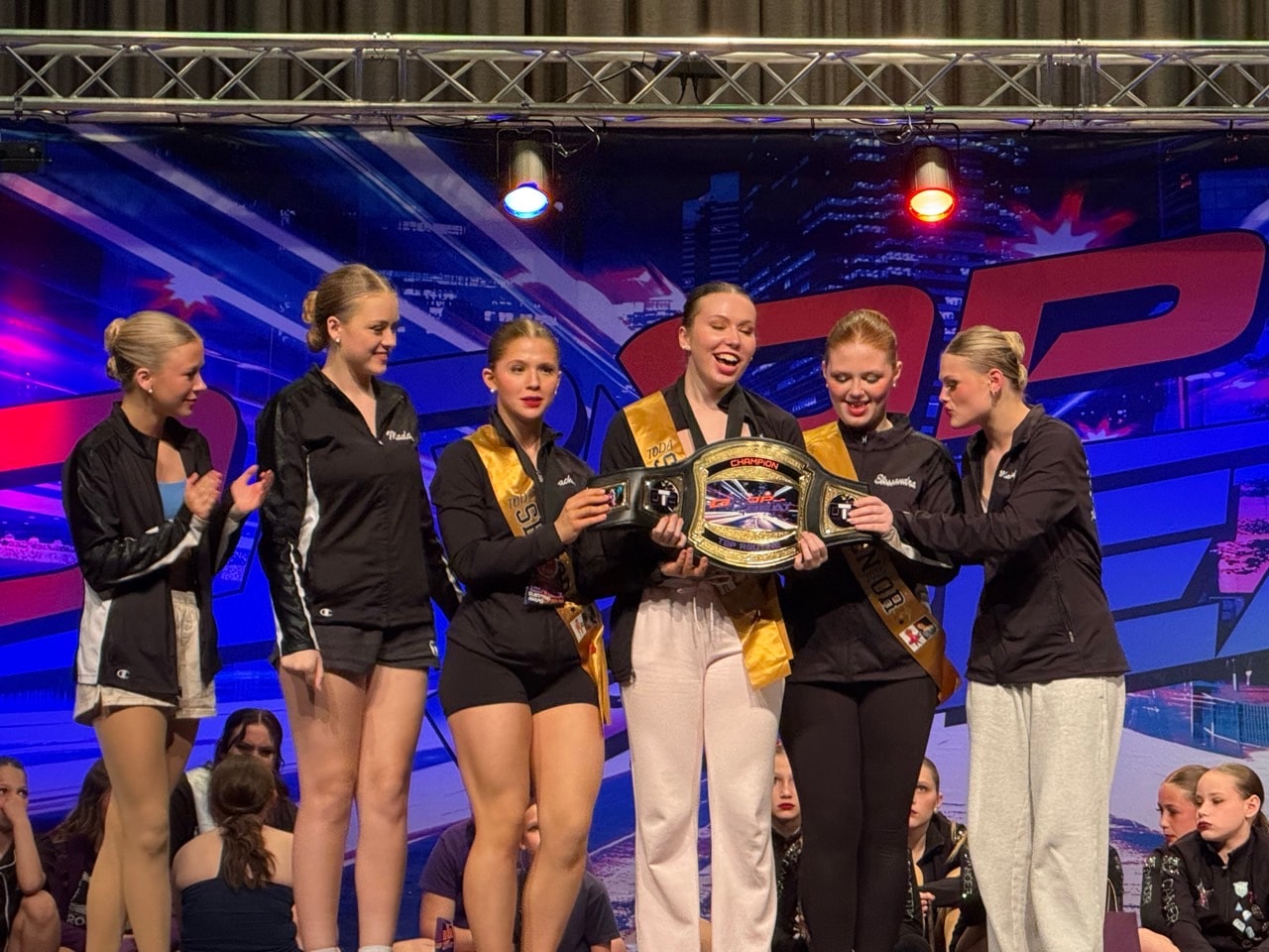 Turn Out Dance Academy dancers celebrating with a championship belt
