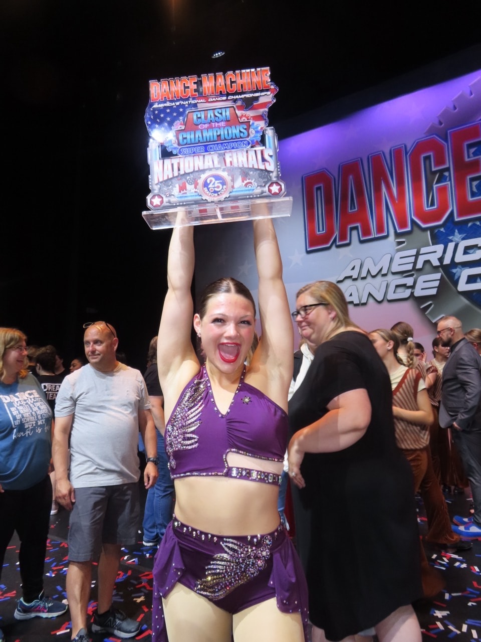 Turn Out Dance Academy performer lifting a championship trophy in celebration