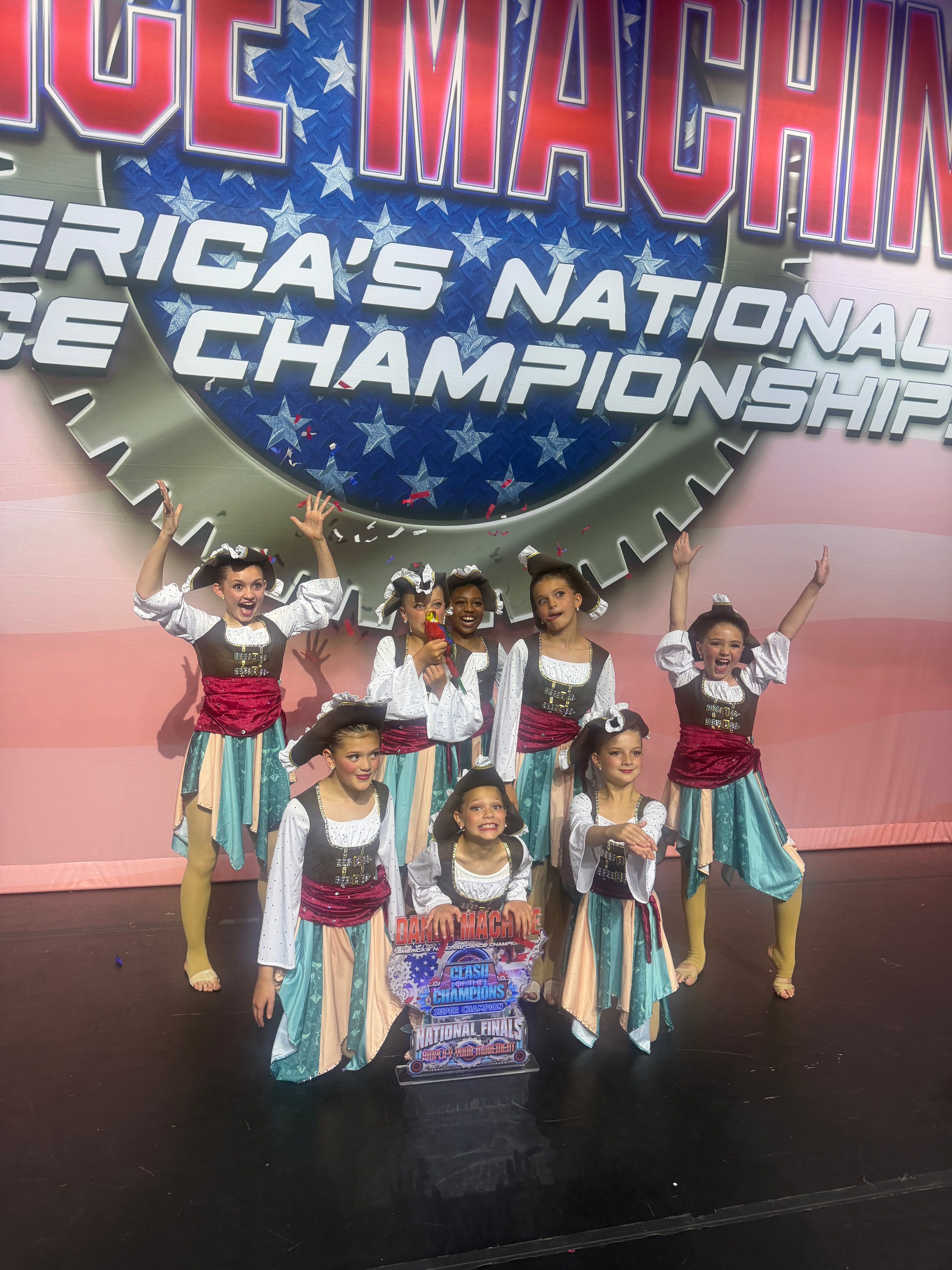 Young Turn Out Dance Academy performers posing with a trophy on stage