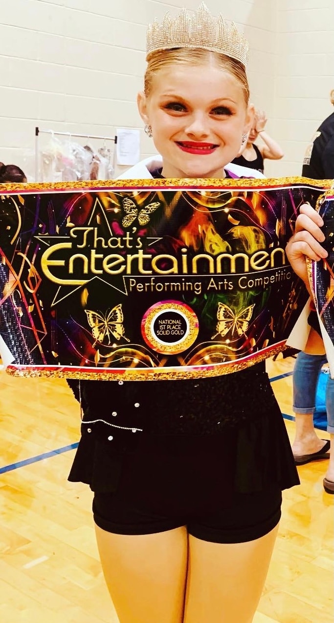 Young Turn Out Dance Academy performer holding a national first-place award banner