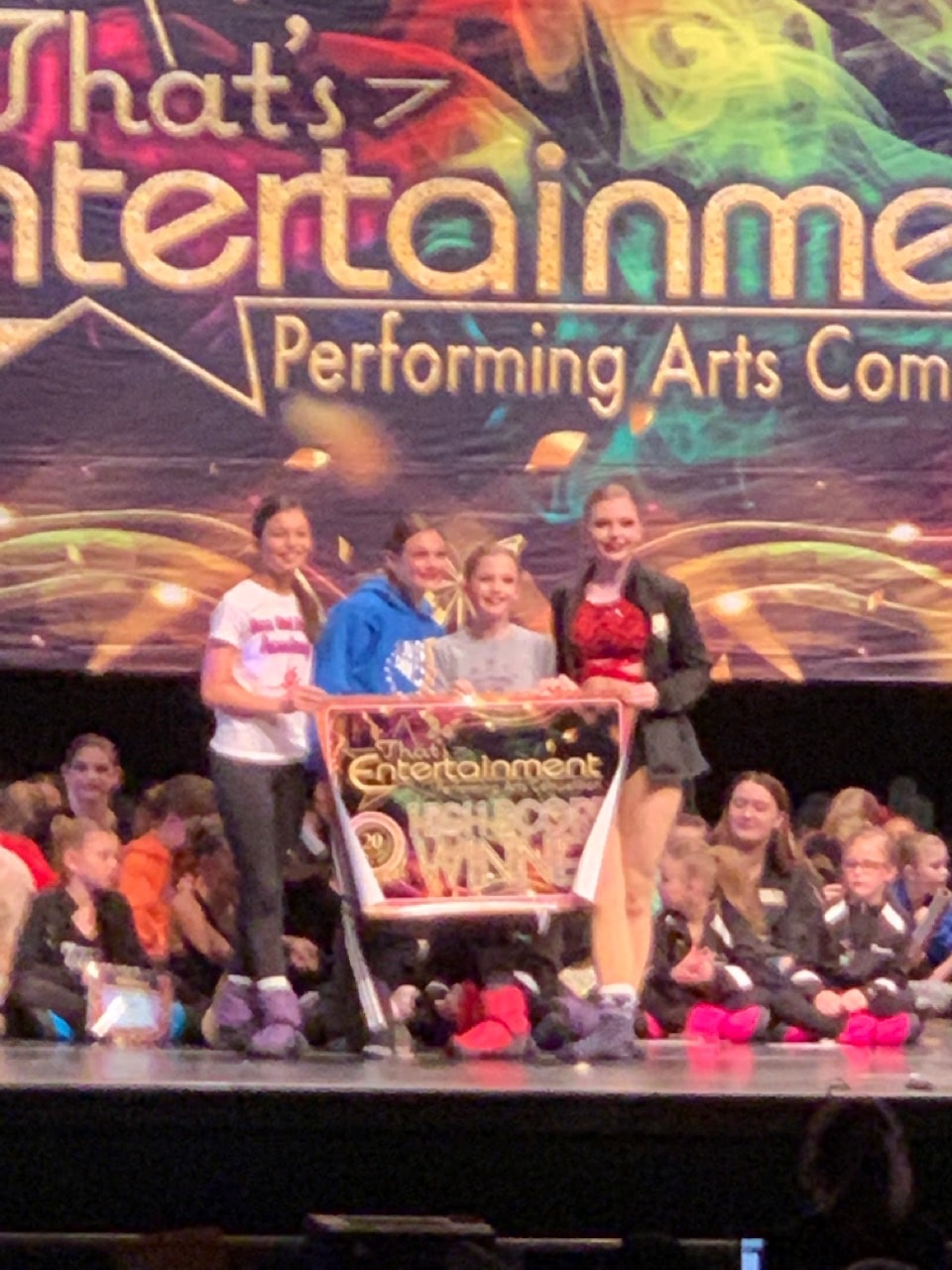 Turn Out Dance Academy performers holding an award banner on a competition stage