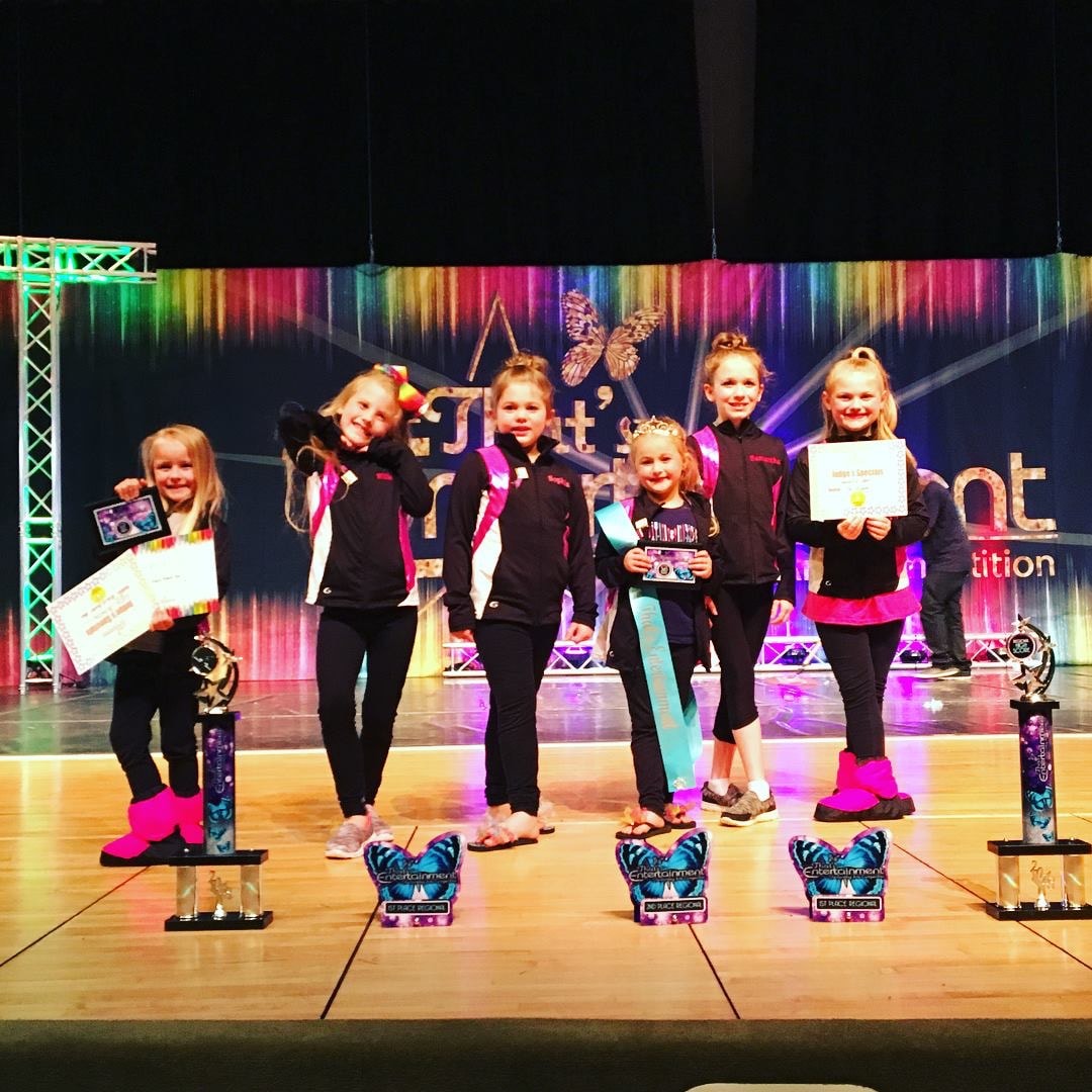 Young Turn Out Dance Academy performers celebrating with trophies and awards on stage