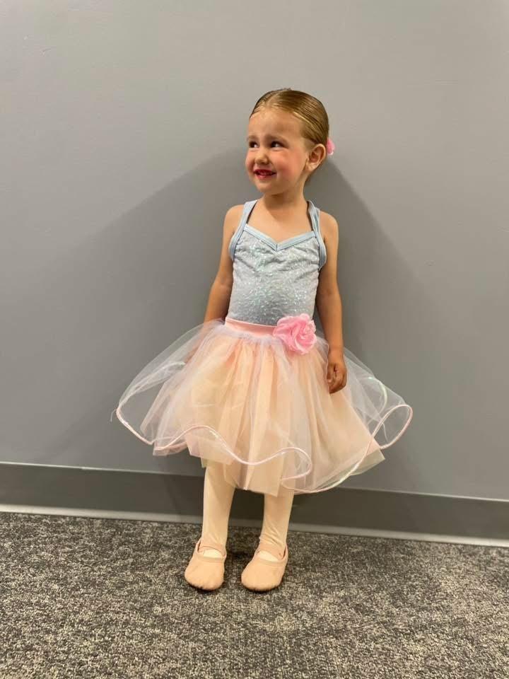 Young dancer posing in a pastel ballet performance costume