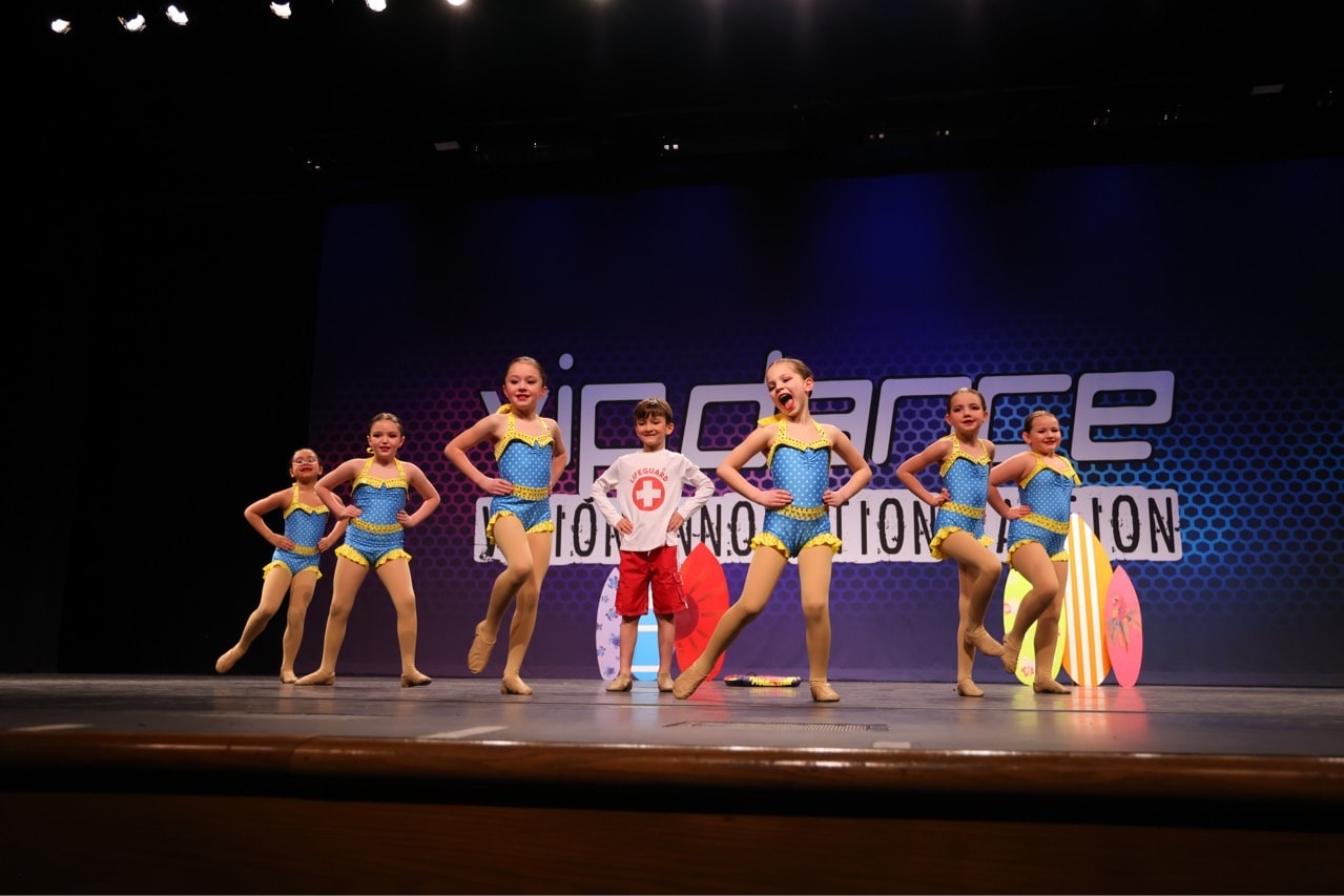 Dance ensemble performing in colorful summer costumes on stage