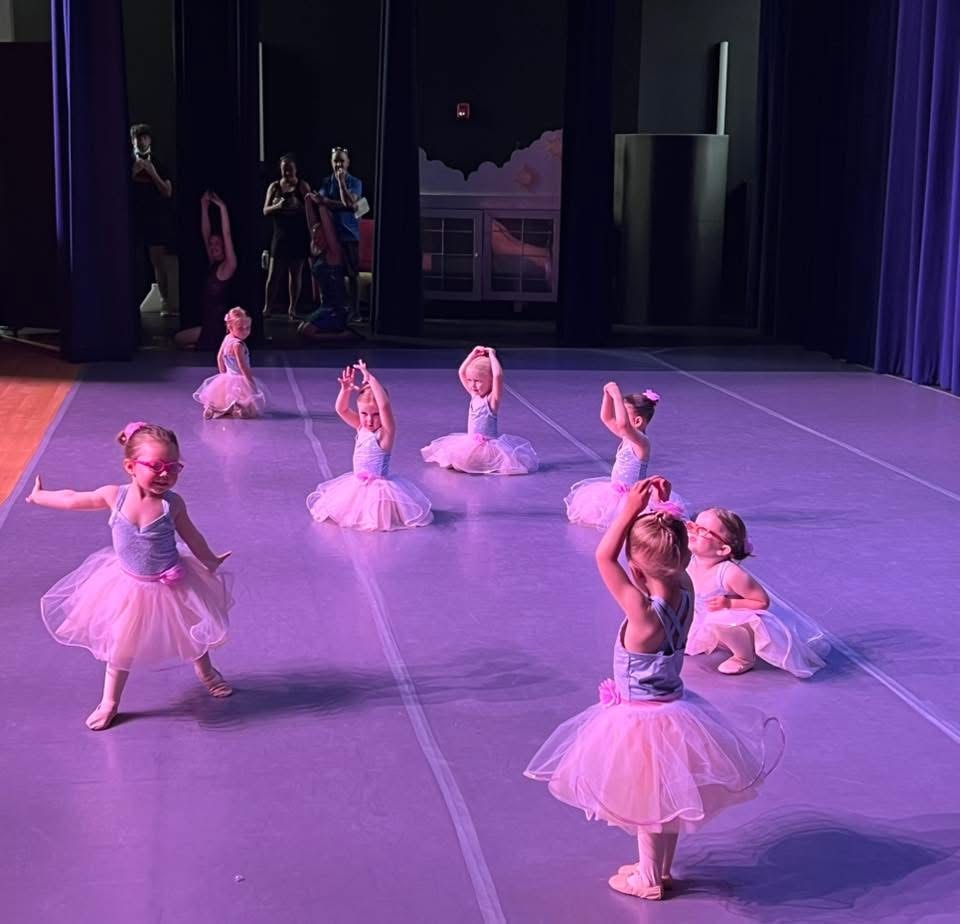 Young ballet dancers performing in pink tutus on stage
