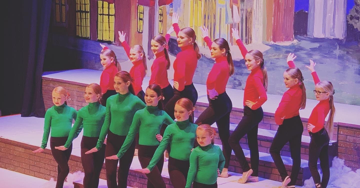 Young dancers performing in colorful costumes on a theater stage