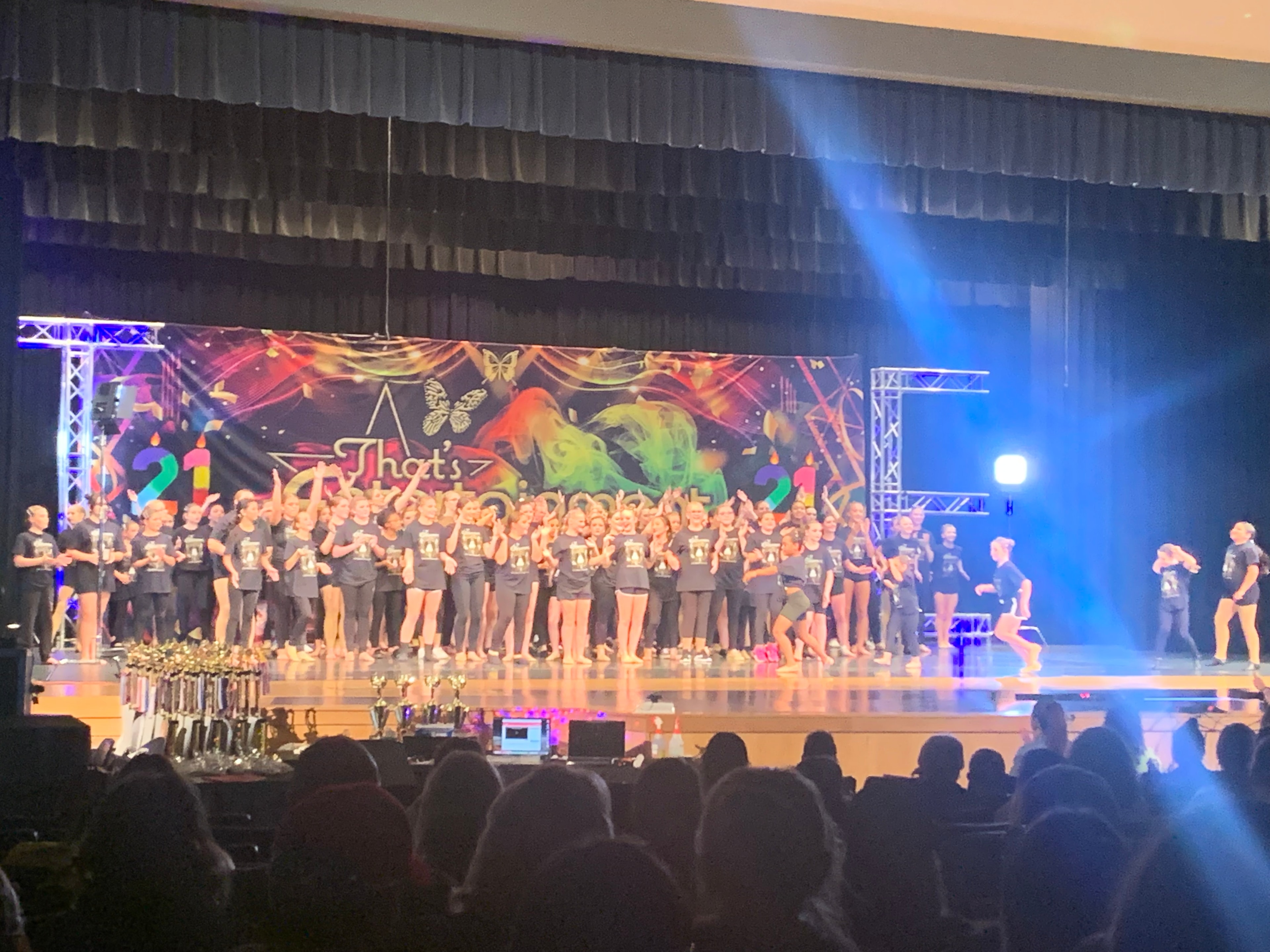 Large group of dancers gathered onstage during a recital celebration