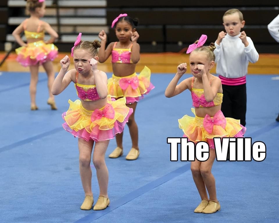 Young dancers performing in colorful costumes on a gymnasium floor