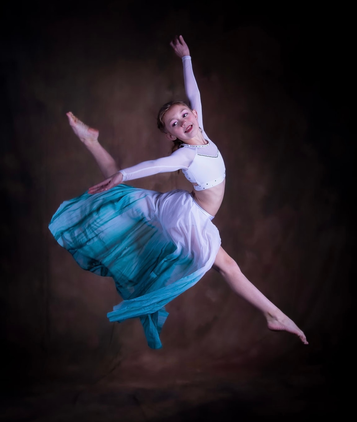 Young dancer leaping in a flowing turquoise and white costume