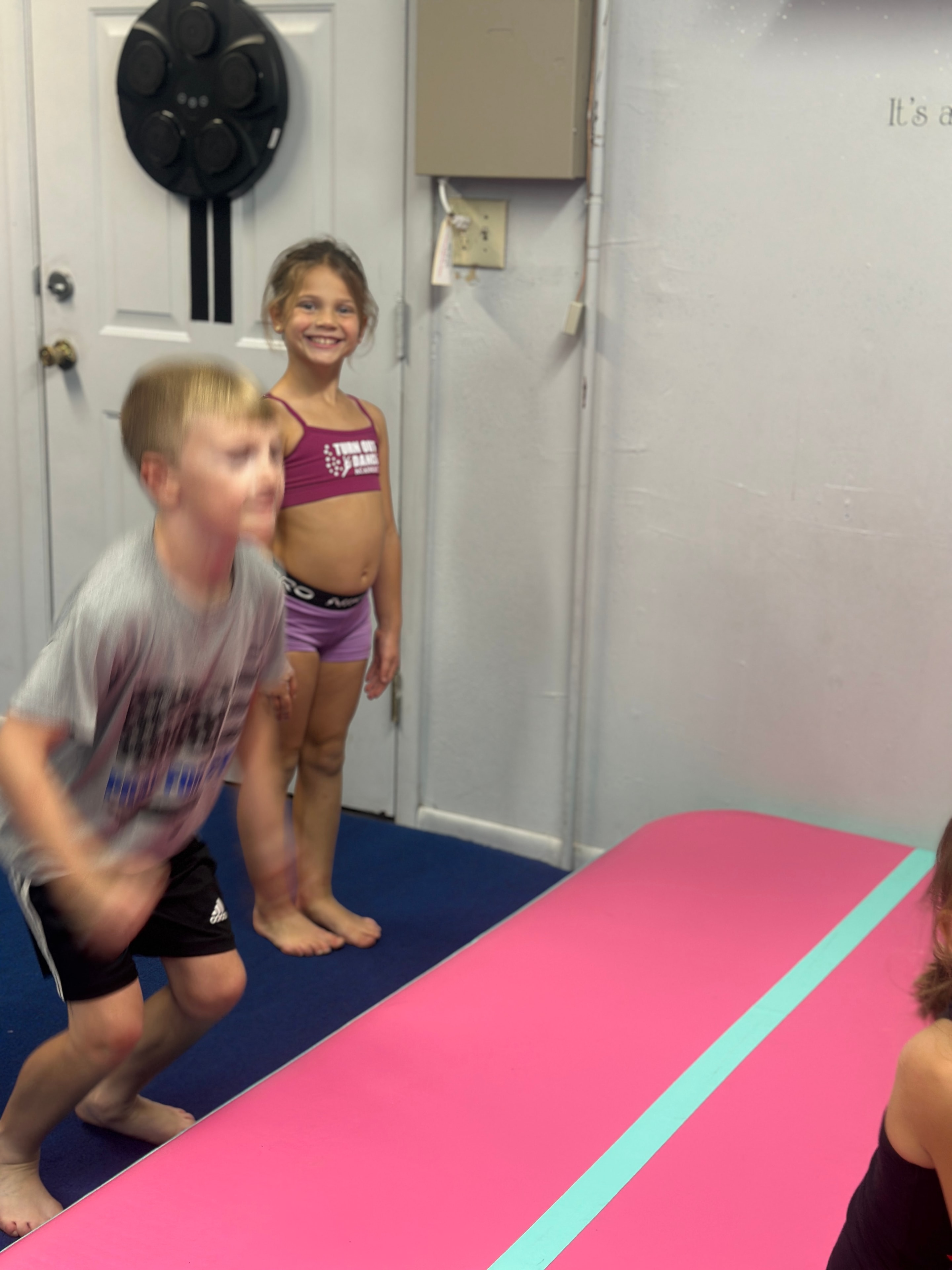 Children practicing movement skills on a colorful gymnastics mat