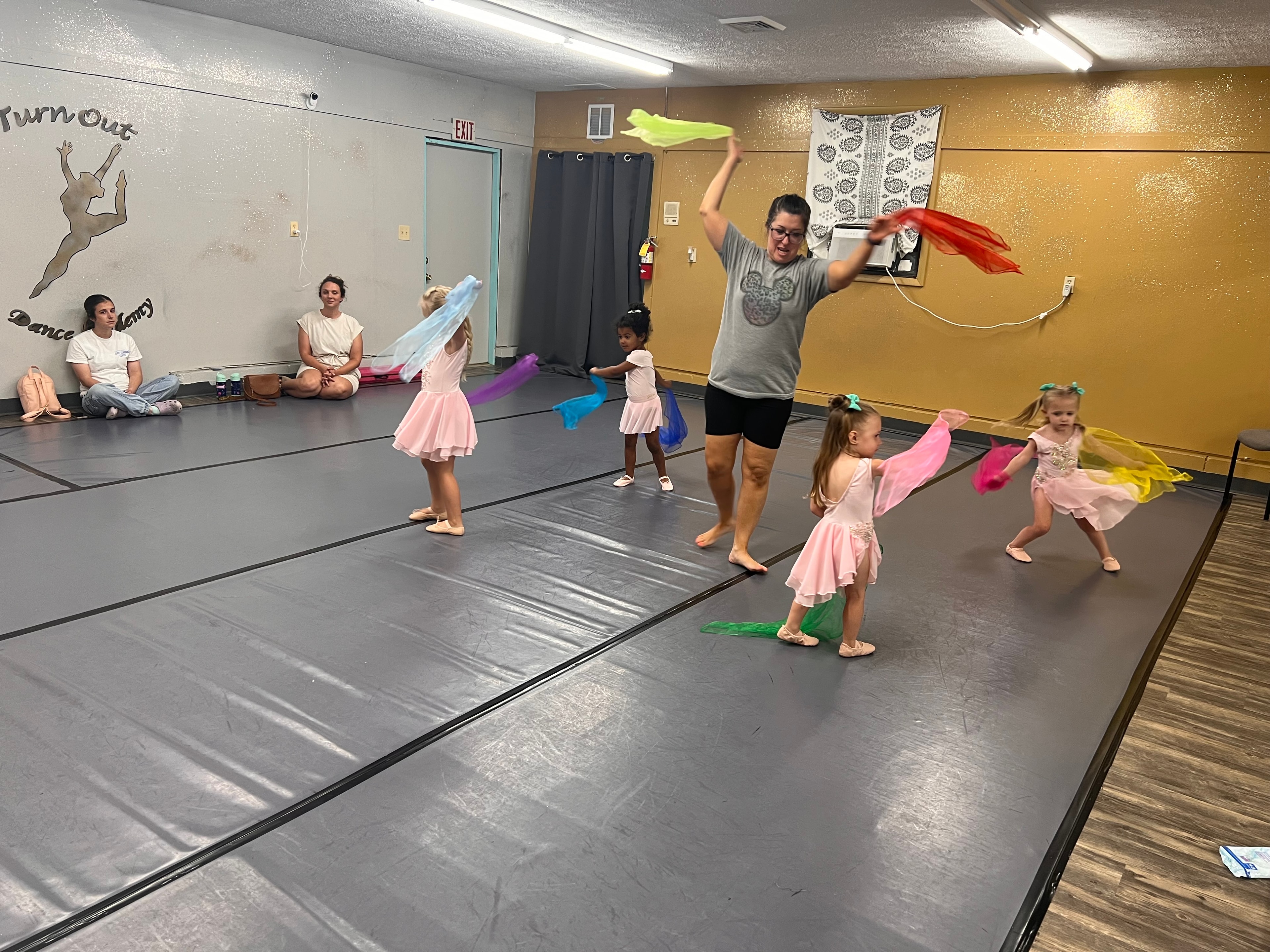 Dance instructor leading young dancers with colorful scarves